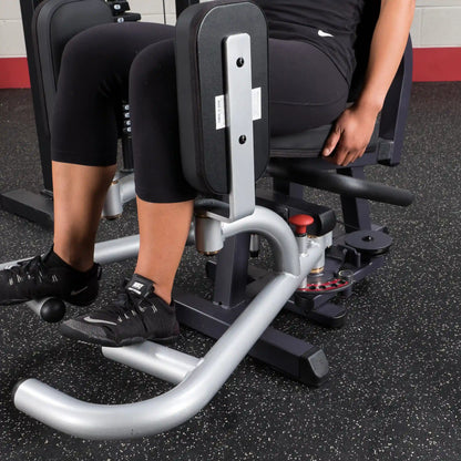 Person using a black leg press machine in a gym.