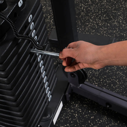 Adjusting weight stack pin on black gym machine for strength training.