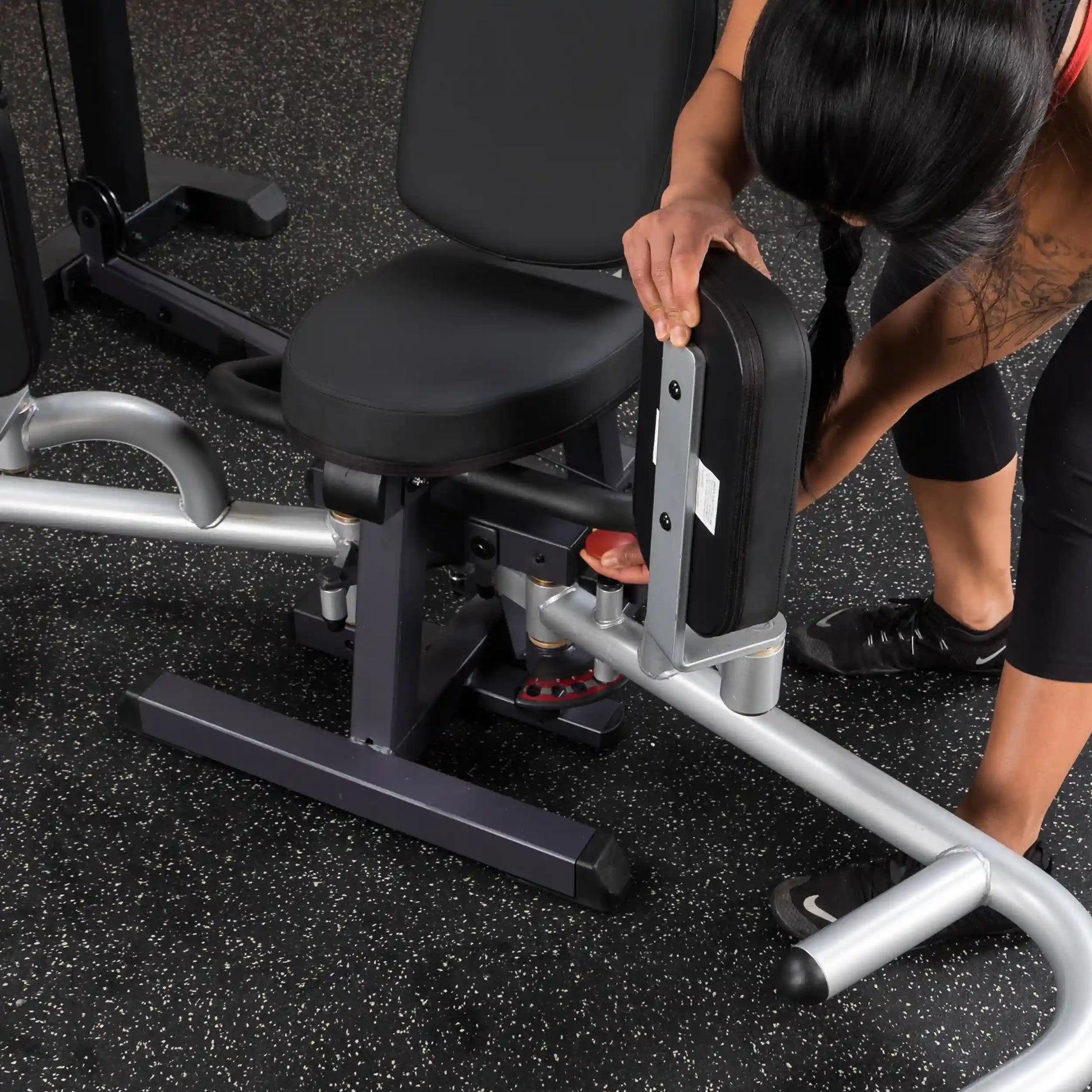 Woman adjusting black weight bench in gym.