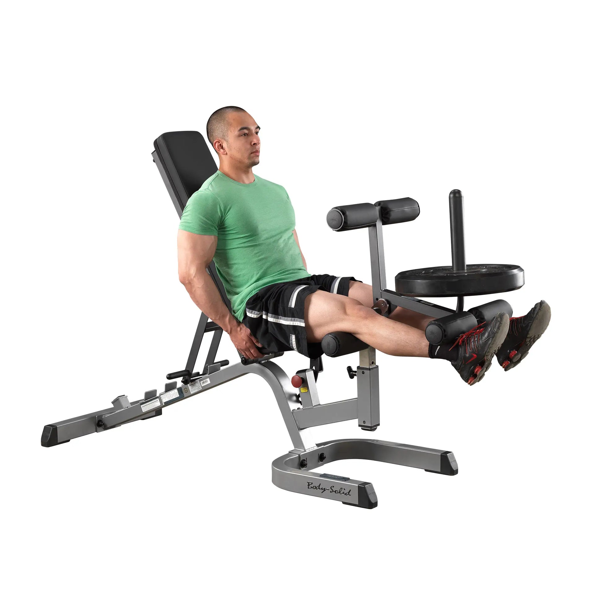Man using Body-Solid leg extension machine in a green shirt for strength training.