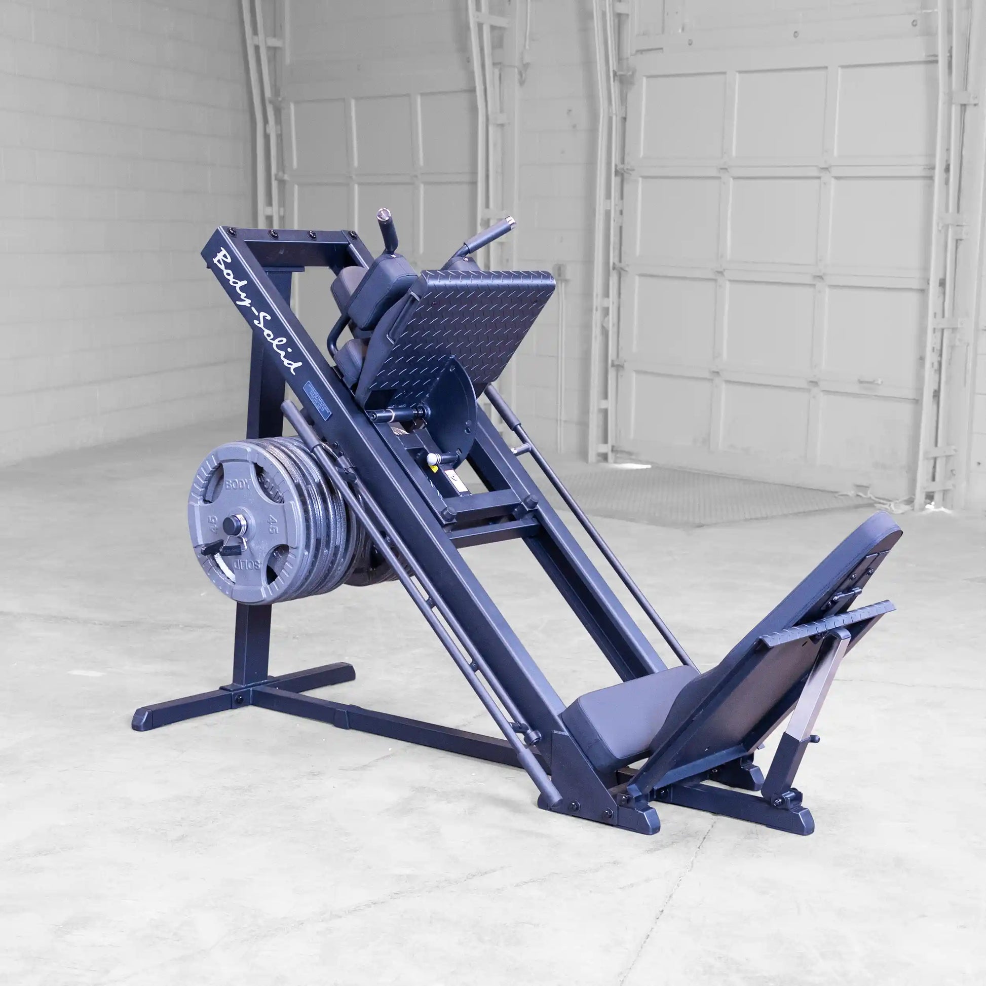 Body-Solid leg press machine with multiple weight plates in a spacious gym.