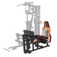 Woman using Body-Solid home gym leg press in gray tank top.