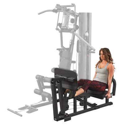 Woman using Body-Solid home gym leg press in gray tank top.
