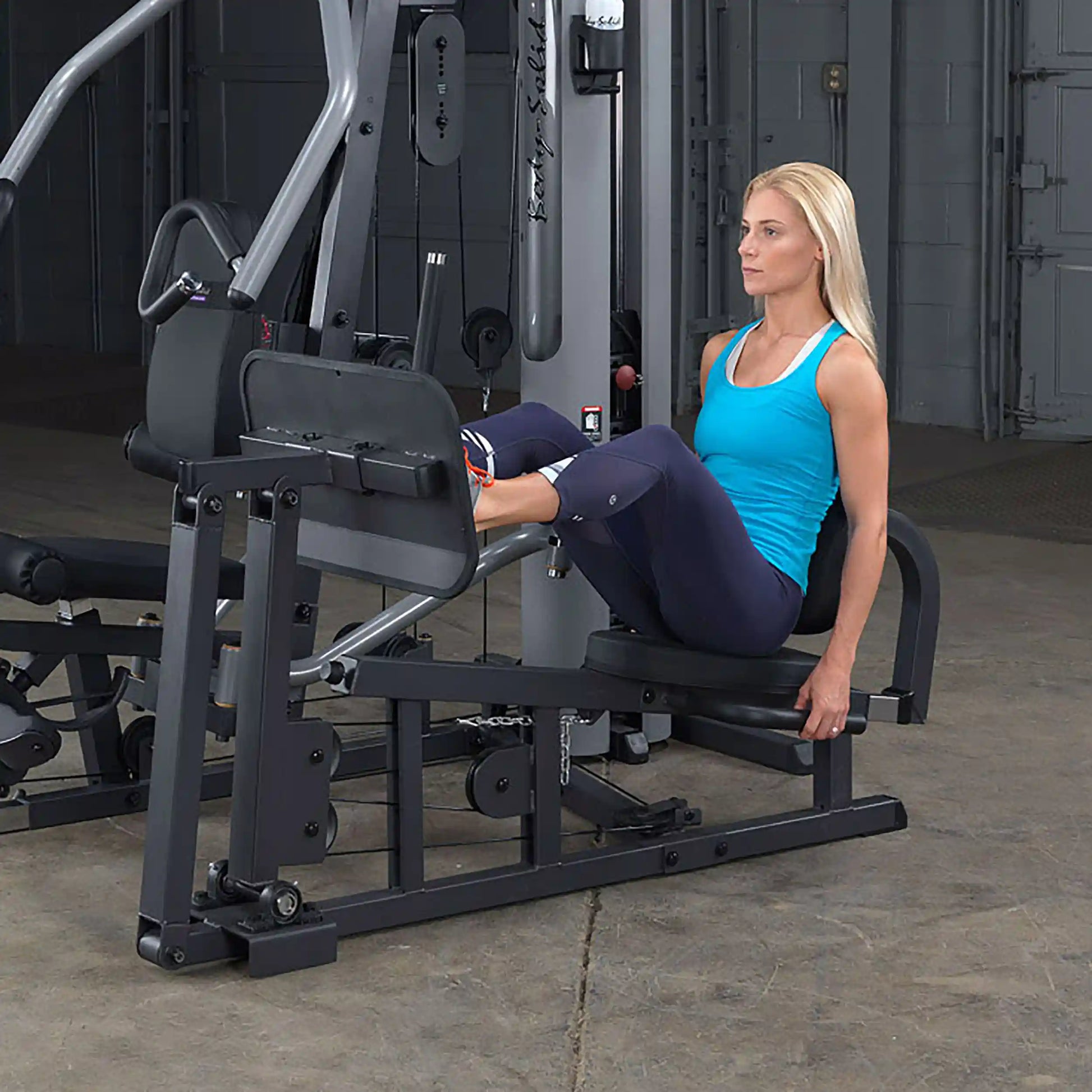 Woman using a Body-Solid leg press machine in a gym.