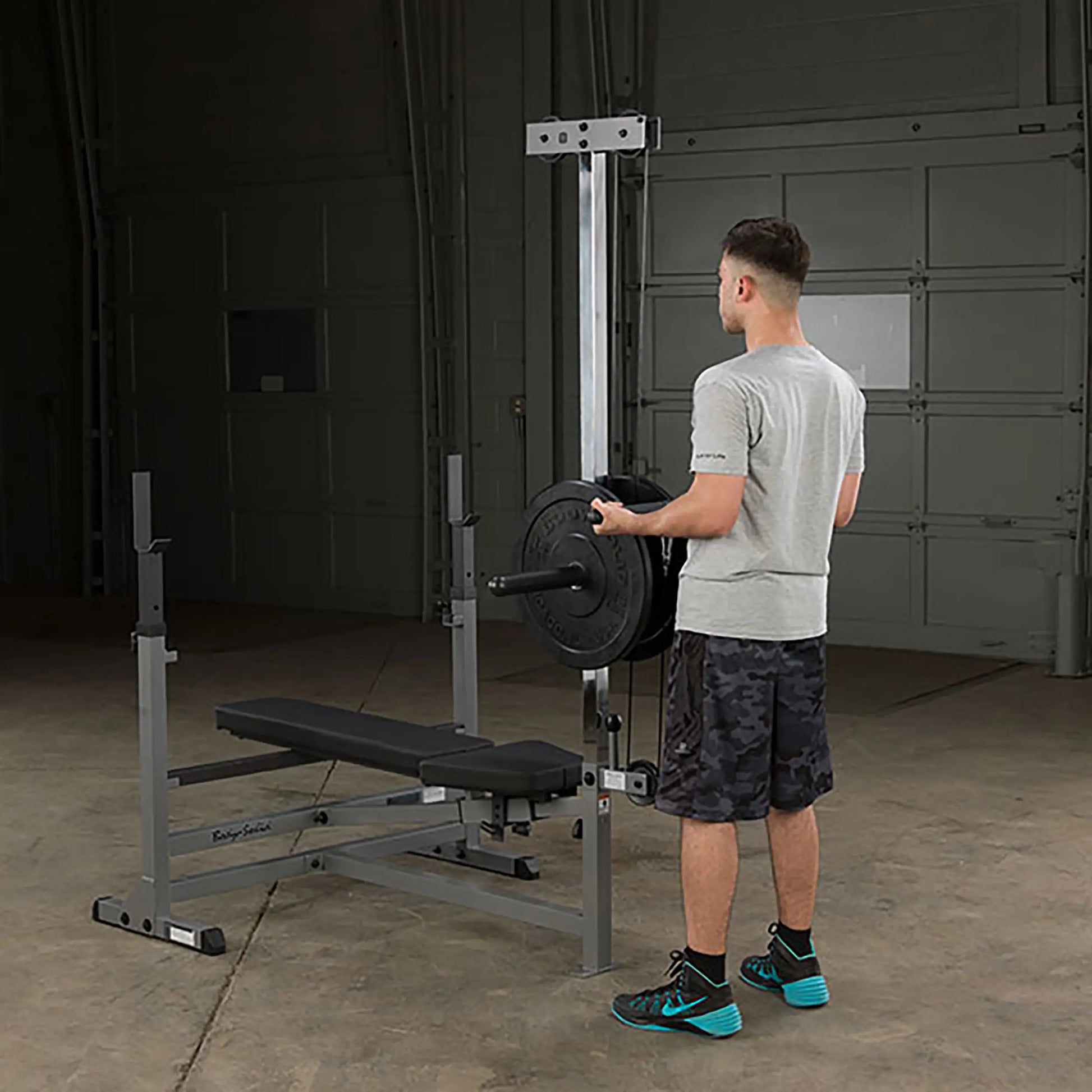 Man loading weights on Body-Solid workout bench in garage gym.