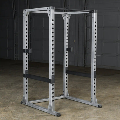 Steel power rack with adjustable safety bars in a gym setting.
