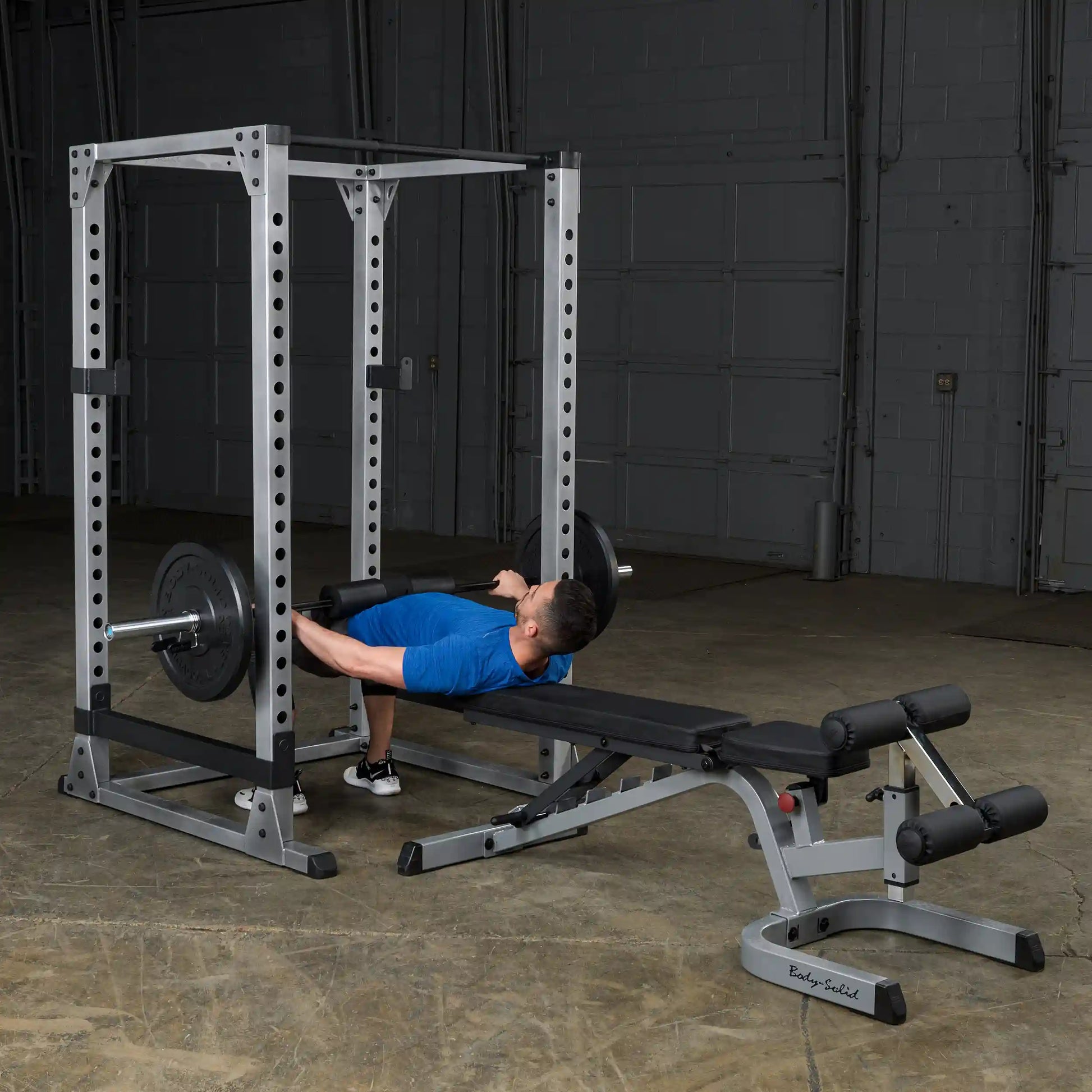 Man performing hip thrust on Body-Solid power rack with padded barbell.