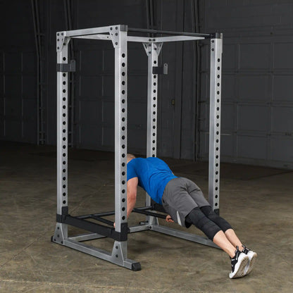 Man performing push-ups on Rogue power rack in blue shirt and black shoes.