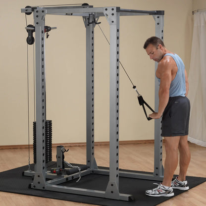 Man using power rack for cable tricep exercise in home gym.