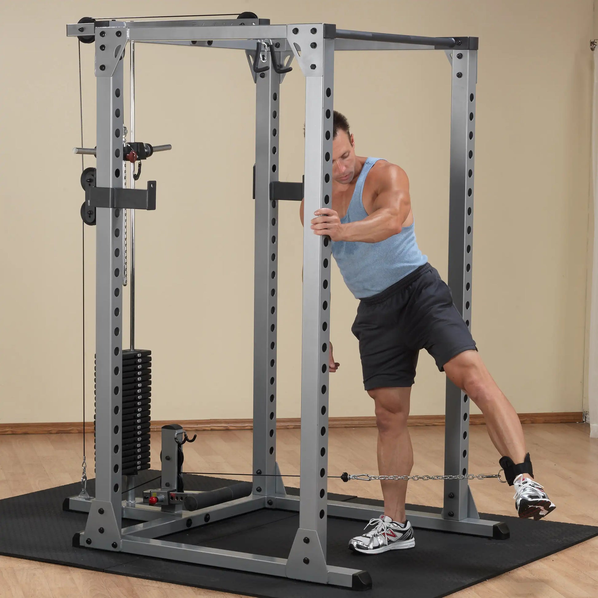 Man using a cable machine for leg exercise in a home gym.