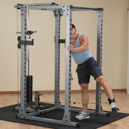 Man using a cable machine for leg exercise in a home gym.