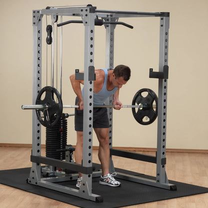 Man using a gray Smith machine for barbell row exercise in home gym.