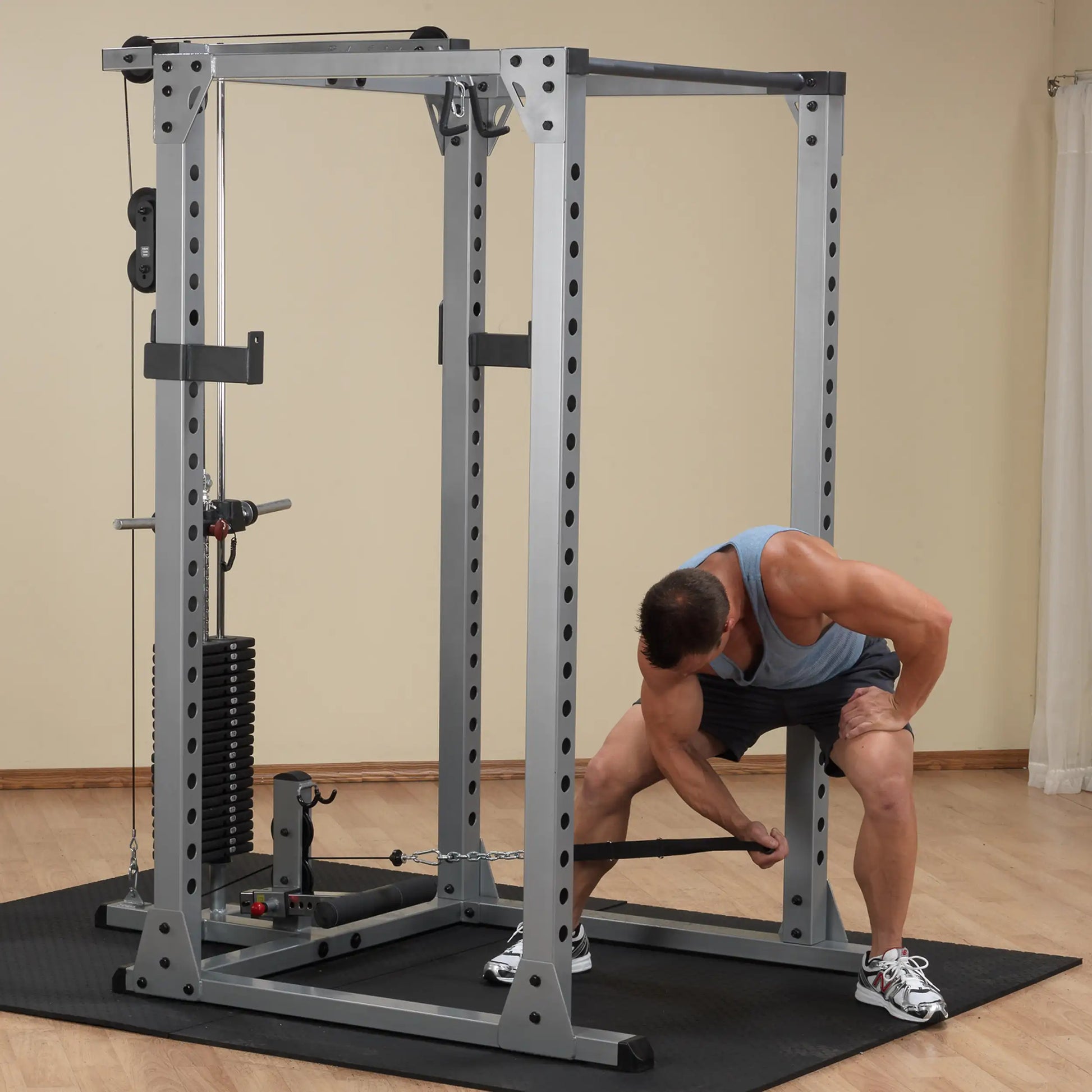Man using a silver power rack with cable system for strength training.