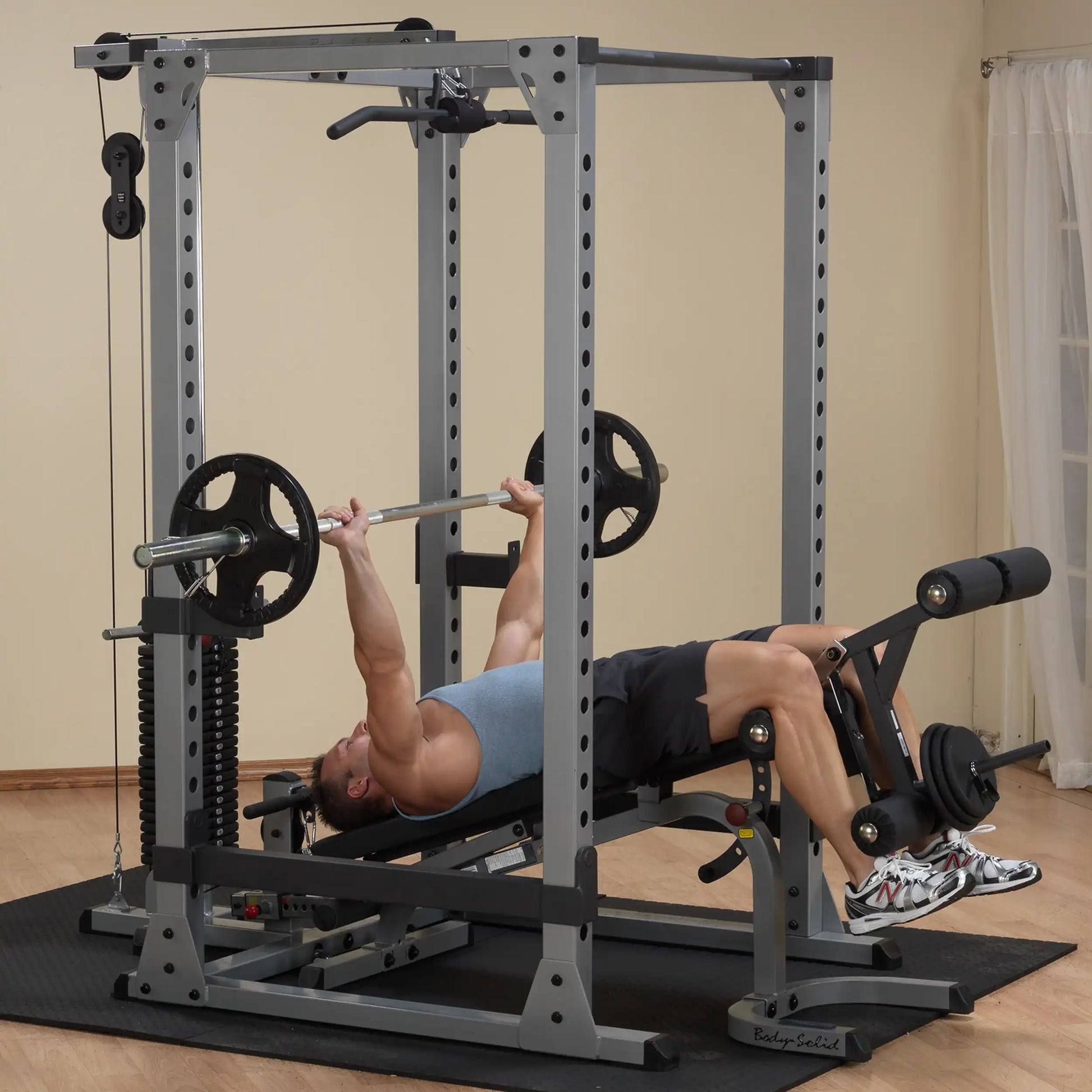 Man using Body-Solid Power Rack for bench press exercise in home gym.