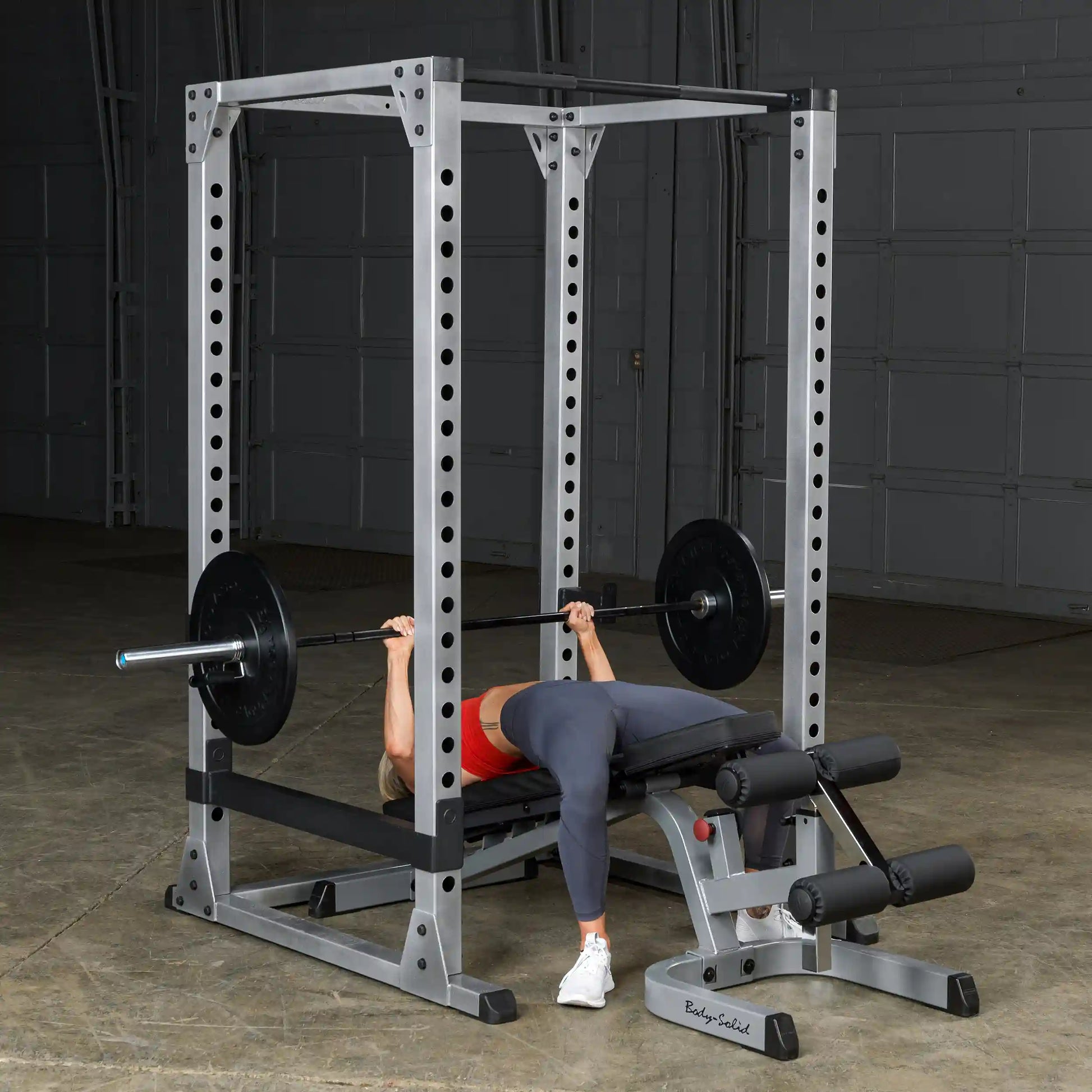 Person bench pressing on Body-Solid power rack in a gym.