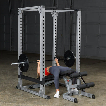 Person bench pressing on Body-Solid power rack in a gym.