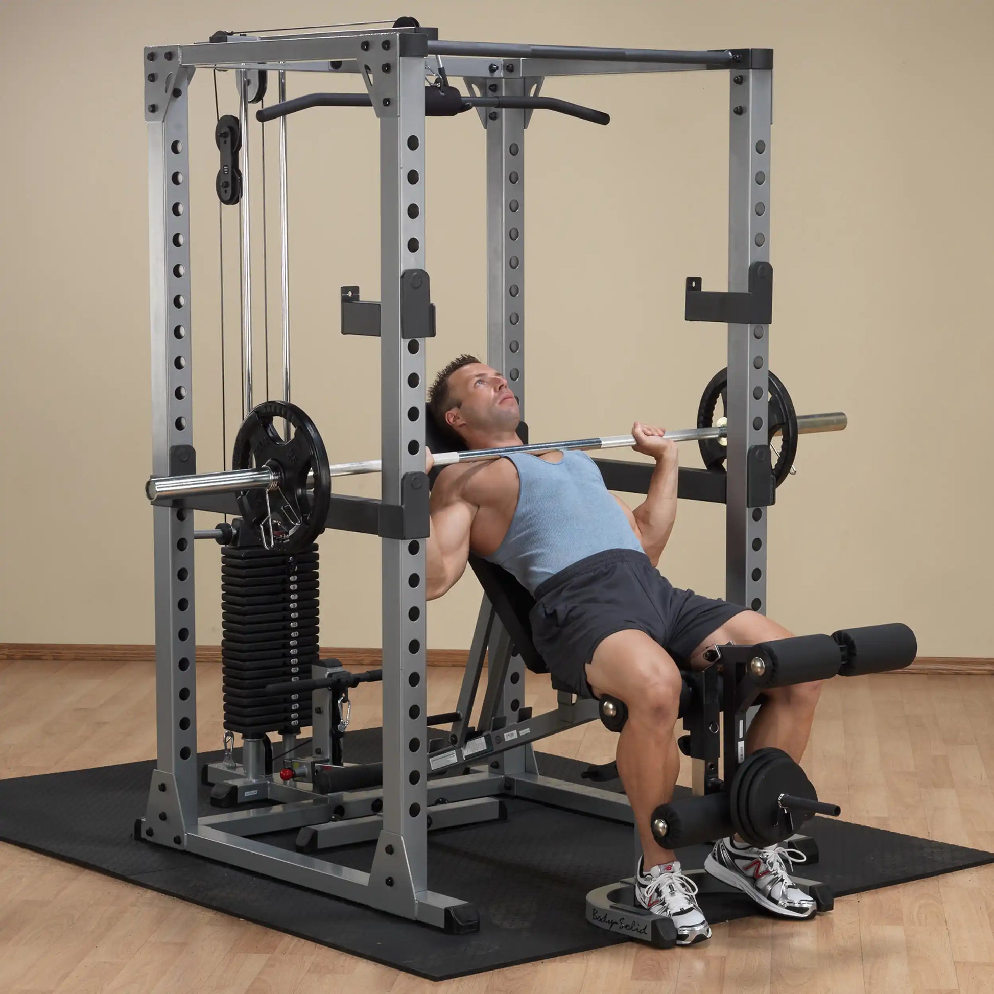 Man using a Body-Solid Smith Machine for bench press in a home gym.