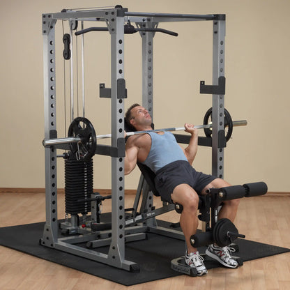 Man using a Body-Solid Smith Machine for bench press in a home gym.