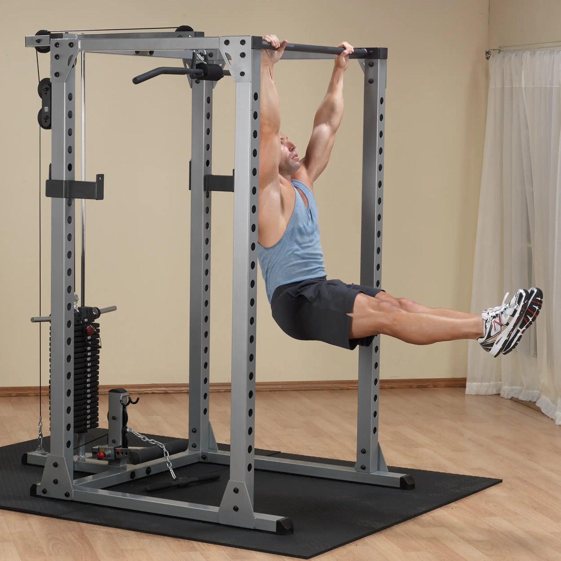 Man performing pull-up on gray power rack in home gym.
