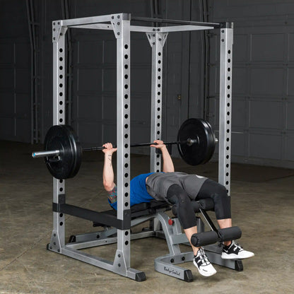 Man bench pressing in a Body-Solid power rack with a barbell.