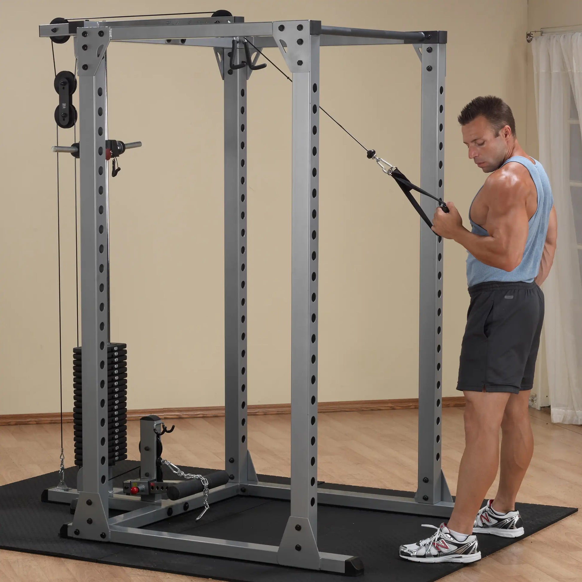 Man using a gray power rack for cable workouts in a home gym.