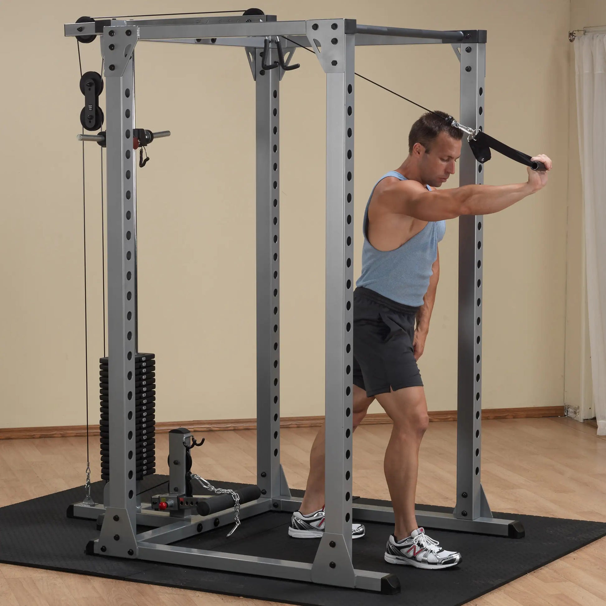 Man using a cable crossover machine for tricep exercises in a home gym.
