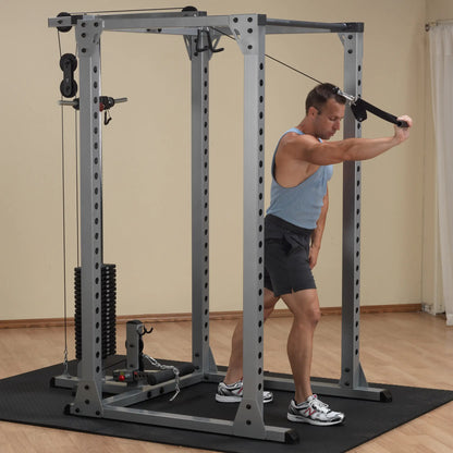 Man using a cable crossover machine for tricep exercises in a home gym.