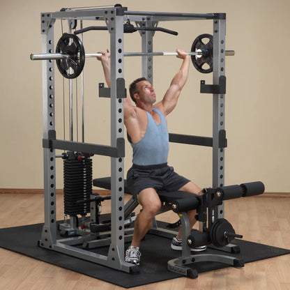 Man lifting weights on a gray Body-Solid power rack in a home gym.