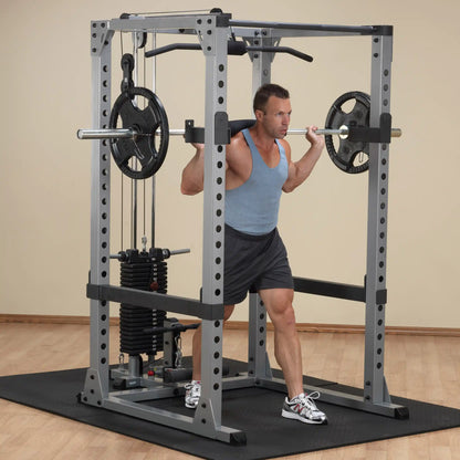 Man lifting weights in a gray power rack, performing squats with a barbell.