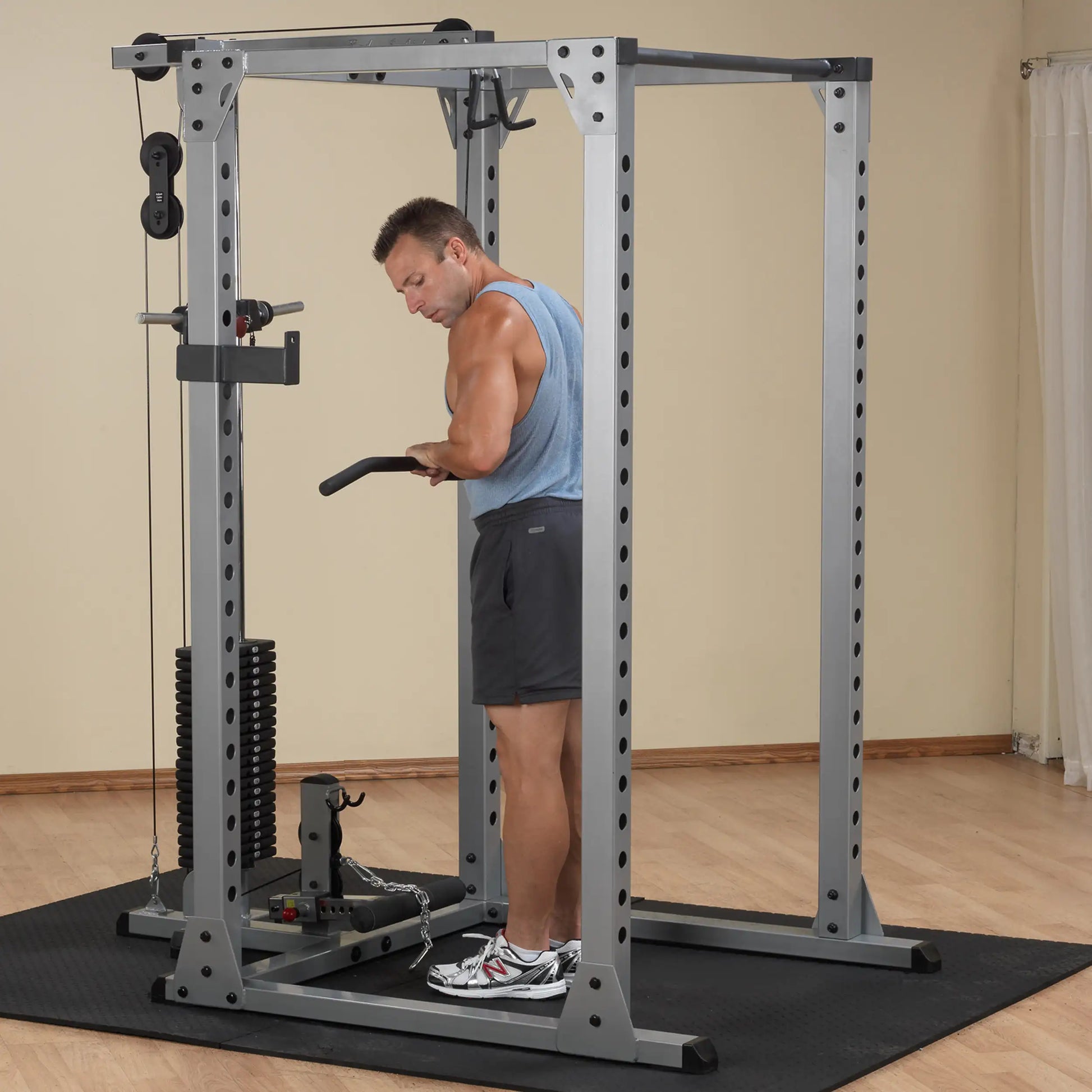 Man exercising on a silver power cage with cable machine in a home gym.