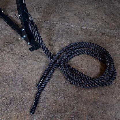 Black battle rope attached to gym equipment on concrete floor.