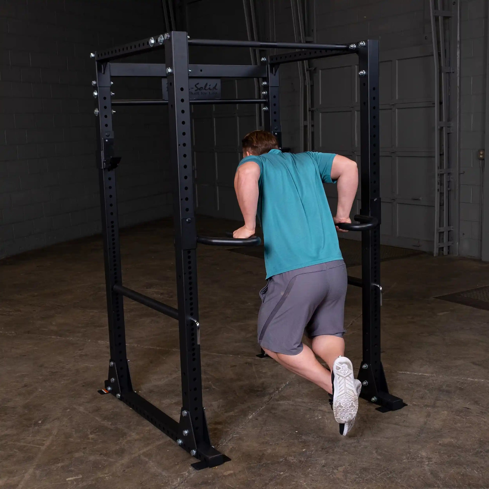 Man performing dips on Body-Solid power rack in a gym.