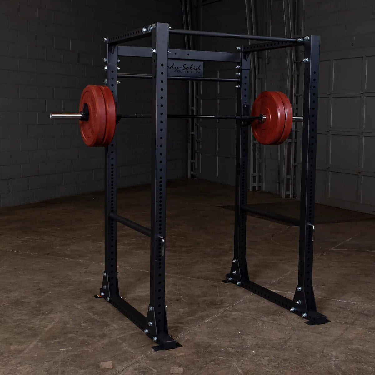 Body-Solid power rack with red weight plates in a gym setting.