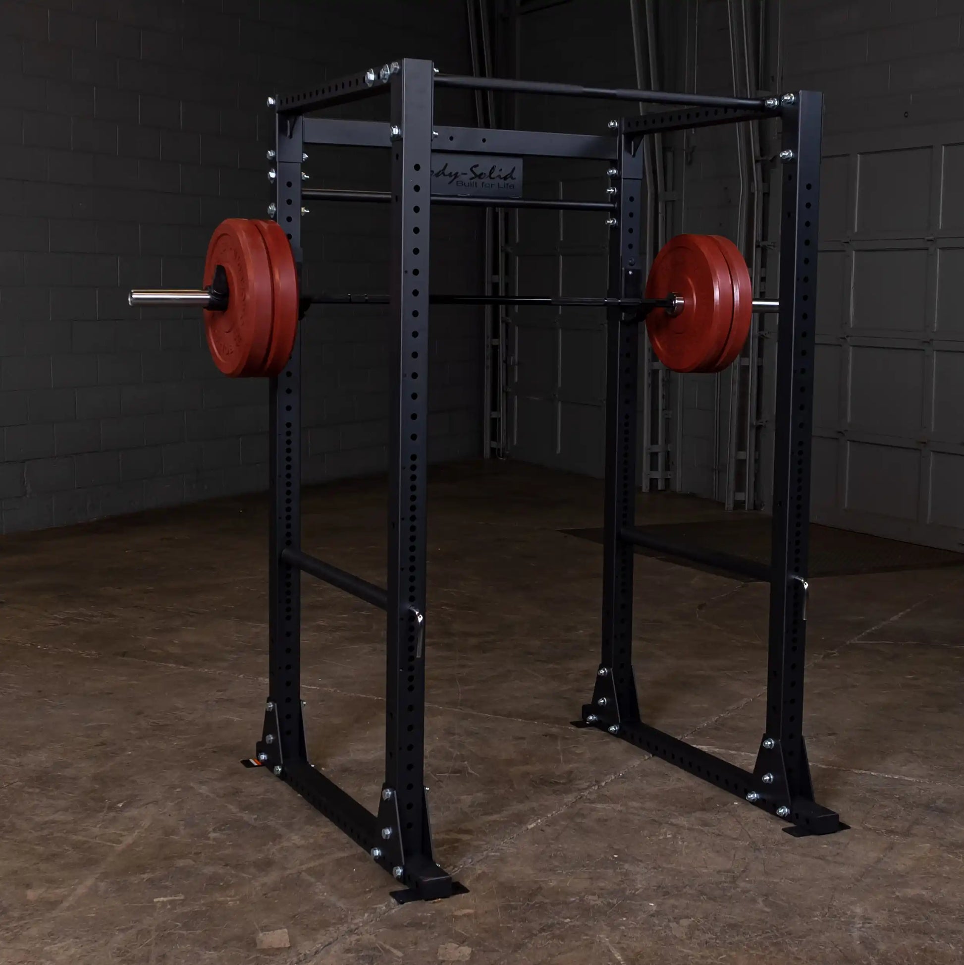 Body-Solid power rack with red weight plates in a gym setting.