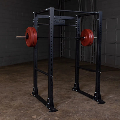 Body-Solid power rack with red weight plates in a gym setting.