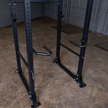 Black power rack with adjustable dip bars in a gym setting.
