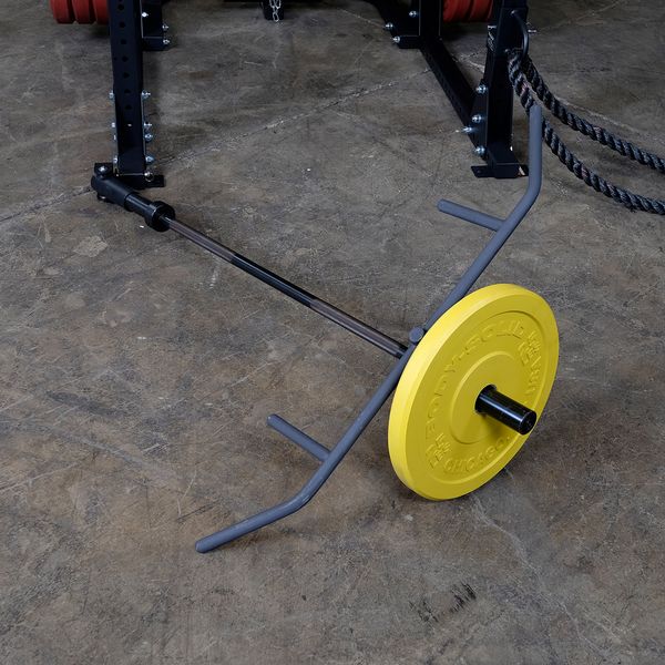 Yellow weight plate on a trap bar in a gym setting with rope attachment.