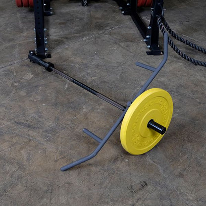 Yellow weight plate on a trap bar in a gym setting with rope attachment.