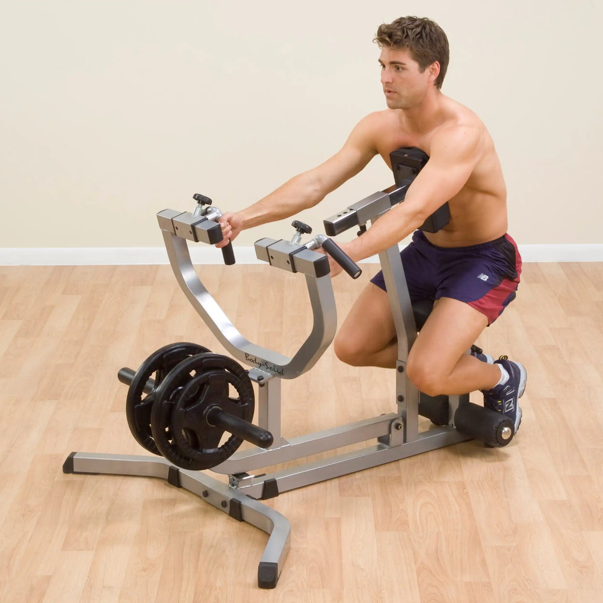 Man using Body-Solid T-Bar Row Machine for strength training on wooden floor.