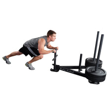 Man pushing Body-Solid power sled with weights for strength training.