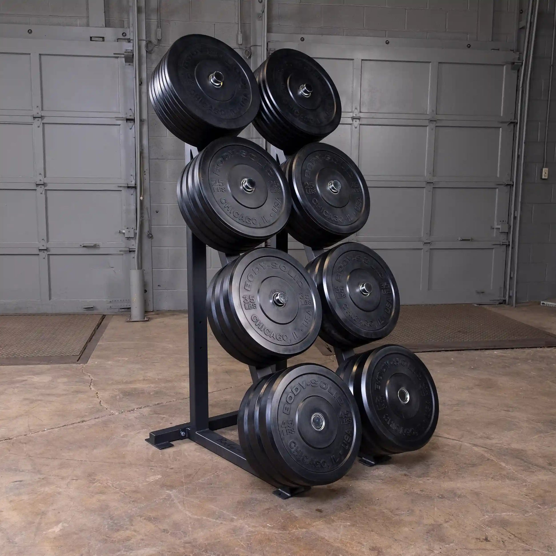 Body-Solid weight plate tree holding black weight plates in a garage gym setting.
