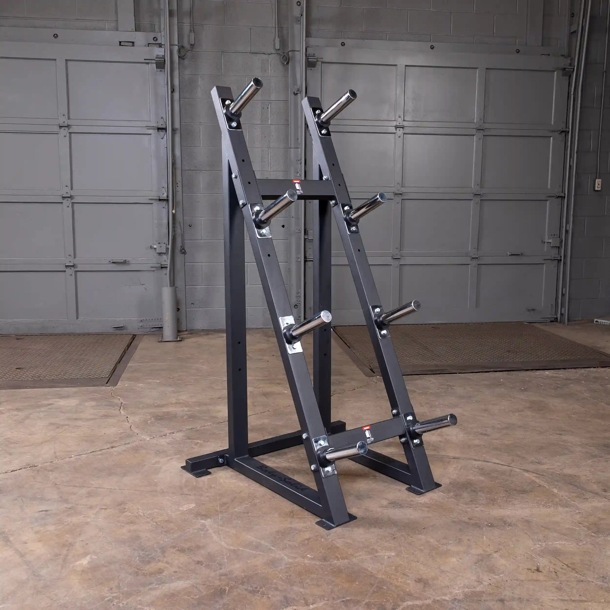 Steel weight plate tree in a gym with multiple storage pegs for organized weightlifting equipment.