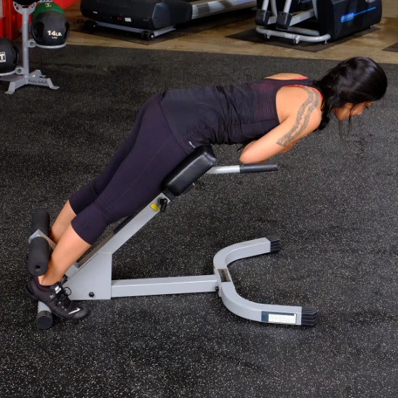A person performing an exercise on a gym equipment designed for back extensions, wearing athletic clothing and focusing on their workout.