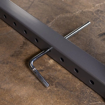 Close-up of a gray metal bar with multiple holes and a chrome hook attached, resting on a textured surface.