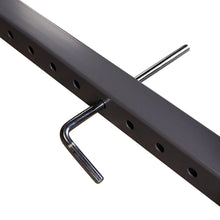 Close-up of a metal bar with multiple holes for adjustments and a metal pin inserted, designed for strength training equipment.