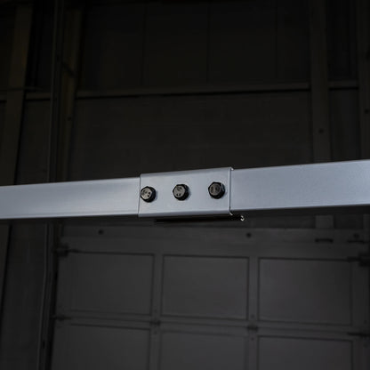 Close-up view of a metallic structure featuring a horizontal beam with three bolts attached to a connector piece, against a dark background.