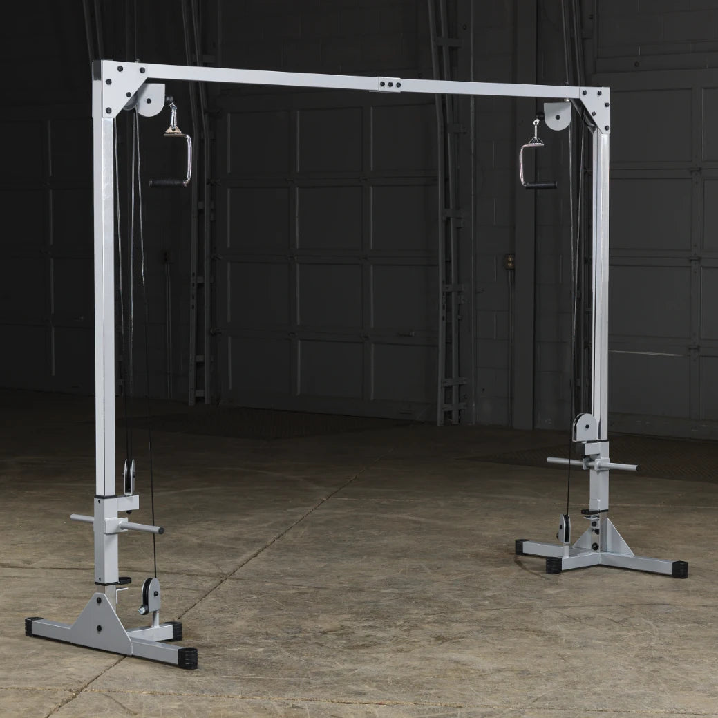 A functional cable machine for strength training, featuring adjustable pulleys and grips, set in an empty gym space with a concrete floor.