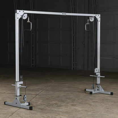 A functional cable machine for strength training, featuring adjustable pulleys and grips, set in an empty gym space with a concrete floor.