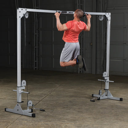 A person performing a pull-up on a pull-up bar in a gym setting, wearing a red shirt and gray shorts, with a focus on upper body strength.
