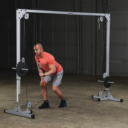 A person performing a cable exercise in a gym, using a cable machine with weights. The individual is wearing a red shirt and gray shorts, demonstrating a focused workout posture.